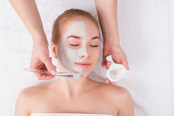 Kobieta dostaje twarz maski przez kosmetyczkę w spa - Zdjęcie, obraz