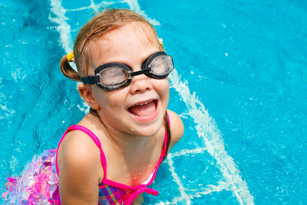 Happy little girl splashing around in the pool - Фото, зображення