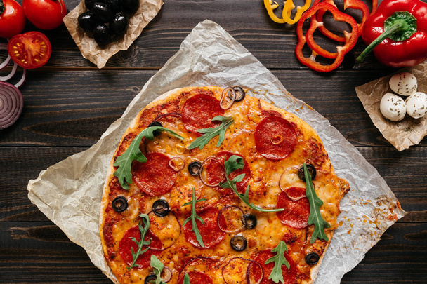 Fresh delicious pizza with pizza ingredients on the wooden table, top view - Фото, изображение