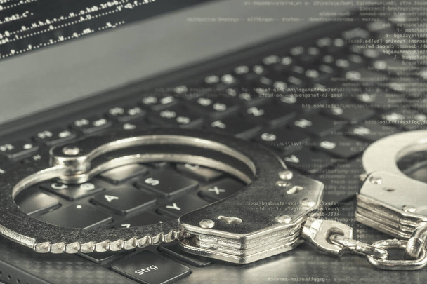 Черно-белые наручники на ноутбуке с цифровым кодом. Концепция хакерской преступности
. - Фото, изображение