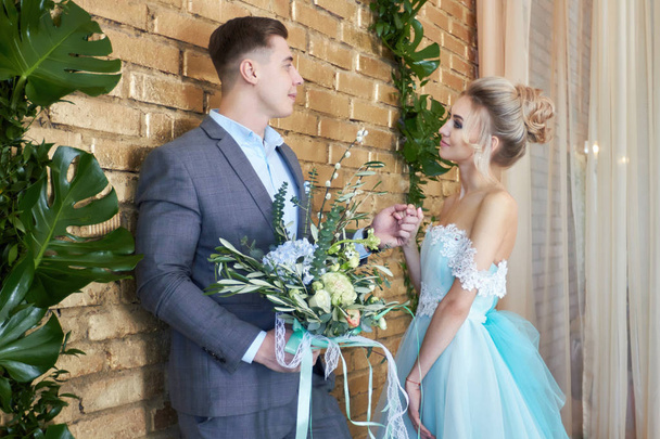 Newly married couple, loving couple before the wedding. Man and woman loving each other. The bride in the turquoise dress and groom in a blue suit. Wedding decor, wedding photo zone - Foto, Imagen