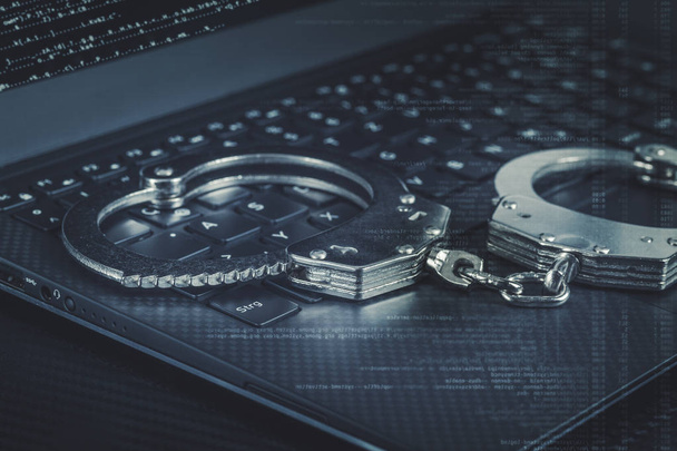 наручники на ноутбуці з синім цифровим кодом навколо. концепція кібер хакерської злочинності
. - Фото, зображення