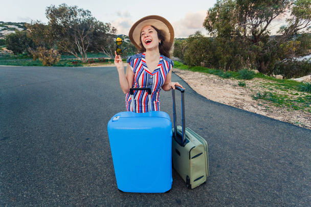 Onnellinen nauraa nuori nainen matkalaukut tiellä
. - Valokuva, kuva