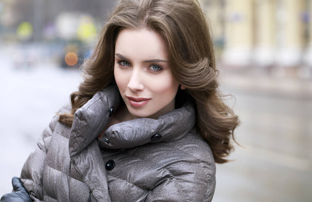 Portrait of a Young stylish brunette girl in a gray down jacket  - Φωτογραφία, εικόνα