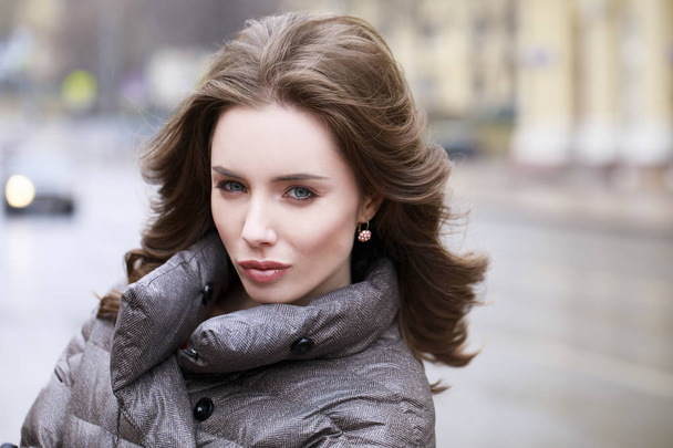 Portrait of a Young stylish brunette girl in a gray down jacket  - Фото, зображення