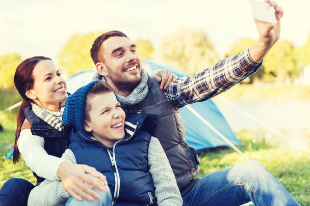 family with smartphone taking selfie at campsite - Valokuva, kuva