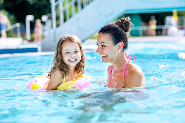 Mother and daughter in swimming pool, aquapark. Sunny summer. - Photo, Image