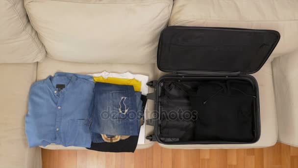 Top view timelapse of packing clothes into a suitcase - Materiał filmowy, wideo