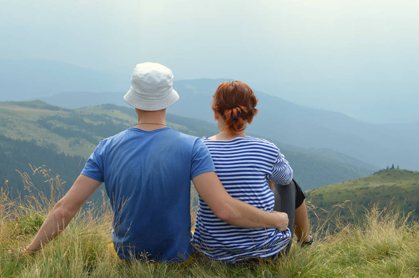 Σιλουέτα του ένα ζευγάρι στην αγάπη κάθεται και ψάχνει ηλιοβασίλεμα θέα στο βουνό. - Φωτογραφία, εικόνα