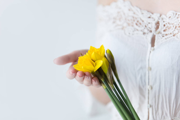 photo of young woman holding bunch of yellow daffodils on the wo - Foto, Bild