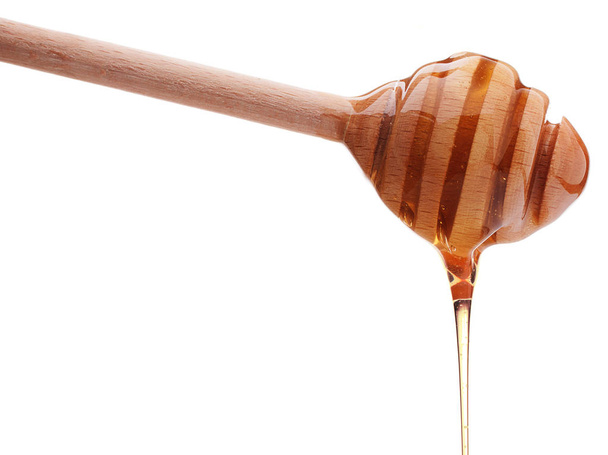 Honey dripping from wooden dipper - Fotoğraf, Görsel