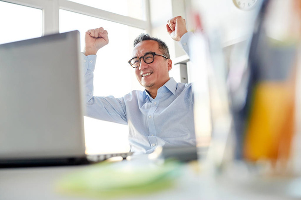 happy businessman with laptop at office - Фото, зображення