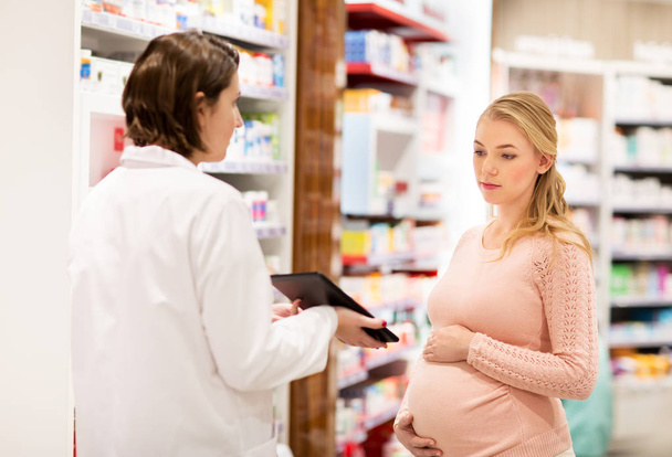 pregnant woman and druggist at pharmacy - Foto, afbeelding
