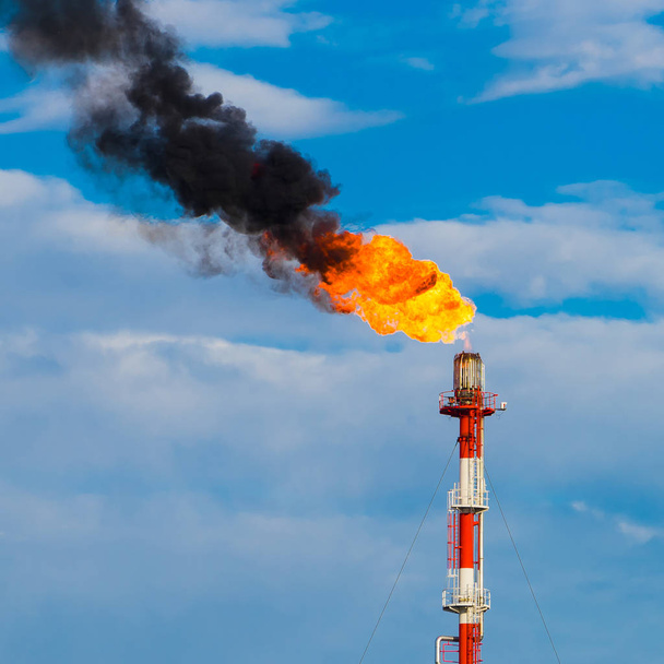 Chimenea de refinería con fuego y humo negro
 - Foto, imagen