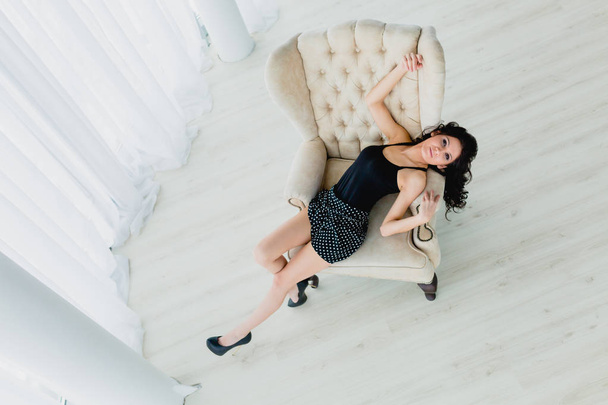 Slender brunette lying on a white armchair - Фото, изображение