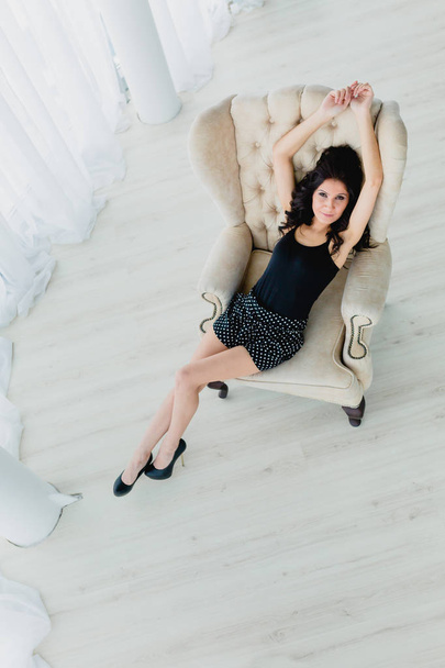 Slender brunette lying on a white armchair - Zdjęcie, obraz