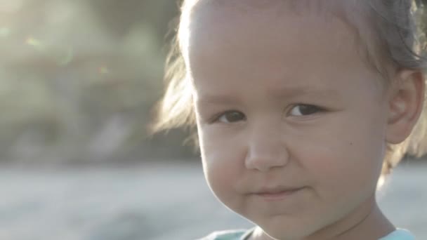 Portret van een meisje op zoek naar camera buitenshuis, close-up - Video