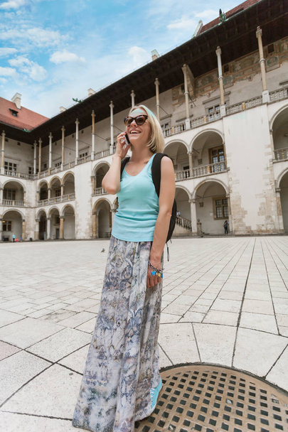 Female traveler on the background of Arcades in Wawel Castle in Cracow. - Фото, изображение