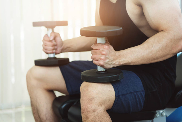 Muscular man lifting dumbbells in gym. copy space. - Фото, изображение