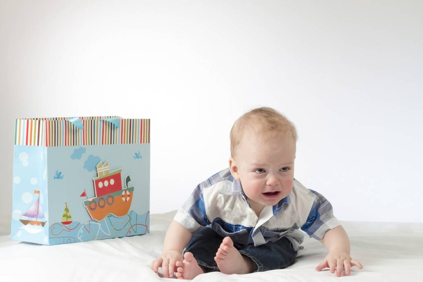 Crying baby boy with a gift package. Sad infant in hysterics. - Photo, Image