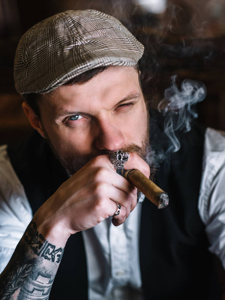A young bearded man smoking a cigar in a pub - Фото, зображення