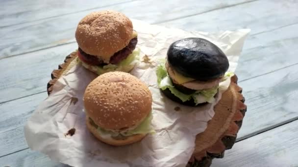 Három hamburgert, fából készült háttér. - Felvétel, videó