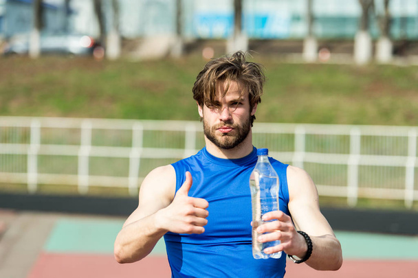 handsome muscular man holds water bottle showing thumb up - Fotoğraf, Görsel