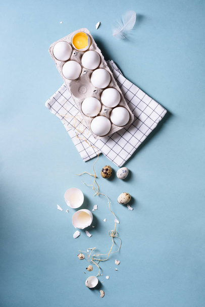 Egg white eggs or chicken eggs in a pack for eggs, quail eggs, food background. Cracked egg with white and yolk over blue. Spring easter theme.  - Фото, зображення