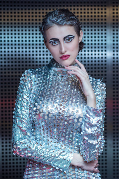 Portrait of young cyber woman in silver futuristic costume with bright makeup. - Фото, изображение