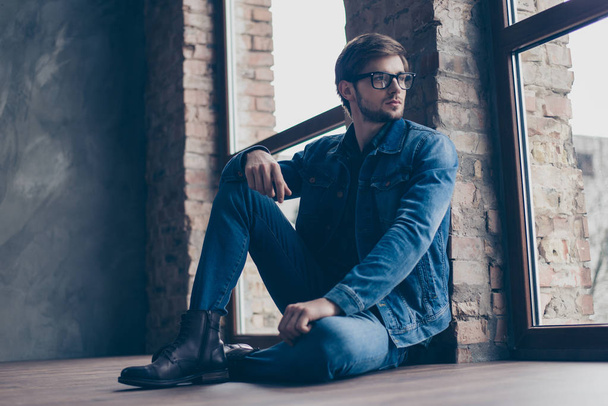 Confident cute smart man with spectacles in jeans sitting on the - Foto, immagini