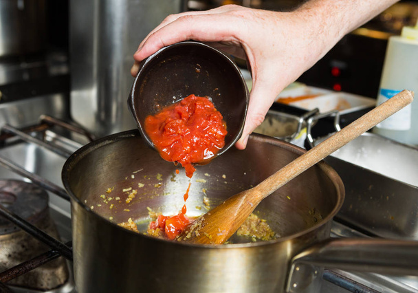 Tomates fraîchement hachées mûries à la vigne biologique, déposées dans une poêle à frire chaude dans le cadre d'une étape de recette
 - Photo, image