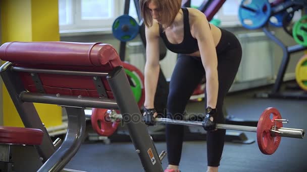 Close up shot of a woman who lifts a dumbbell with a load in a semi-crouch. - Footage, Video