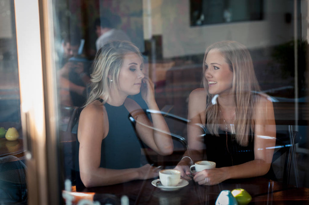 Chica sentada en la ventana de una cafetería bebiendo café
 - Foto, imagen