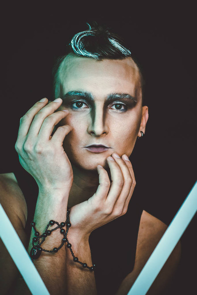 Portrait of beautiful young man with modern hairstyle, artistic multicolor makeup. Studio shot. - Fotó, kép