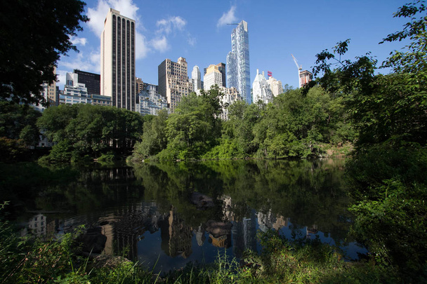 Heijastava järvi Manhattanin varjossa ja rakennuksissa kesällä
 - Valokuva, kuva