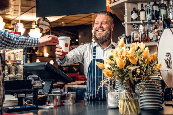 Barista barbuto che vende caffè a un consumatore
 - Foto, immagini
