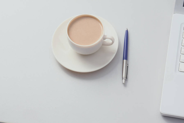 A cup of coffee, paper and a pen on a laptop - Zdjęcie, obraz