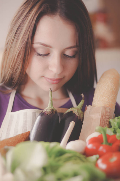 Young woman holding grocery shopping bag with vegetables Standing in the kitchen - Foto, imagen