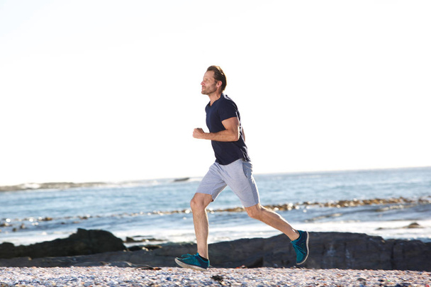 active man running by beach - Foto, immagini