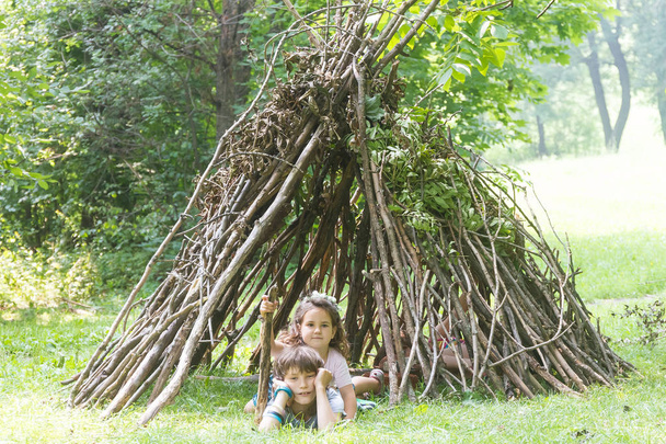 niños jugando al lado de la casa palo de madera
 - Foto, Imagen