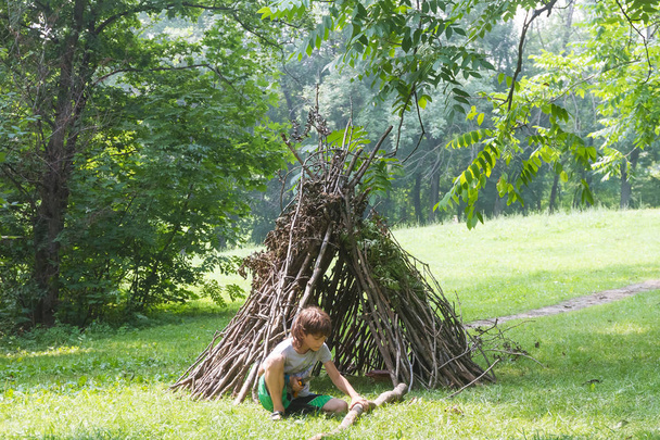 kids playing next to wooden stick house - Photo, Image