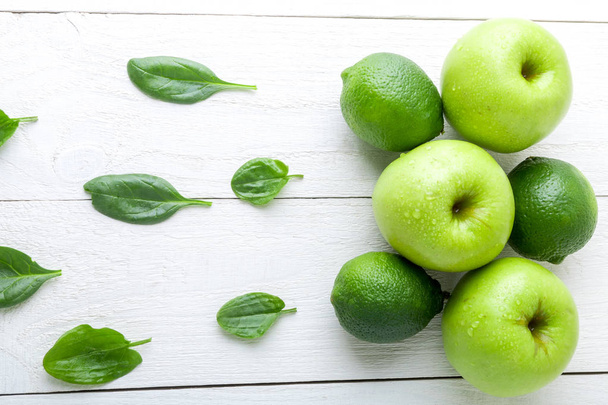 Frutos verdes sobre fondo de madera blanca. Manzana, lima, espinacas. Desintoxicación. Comida saludable. Vista superior. Copiar espacio
. - Foto, Imagen