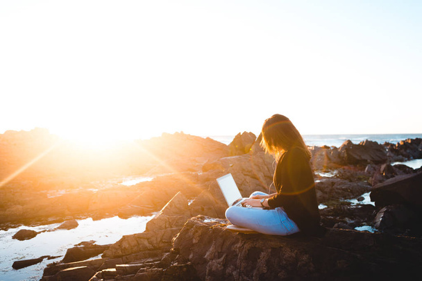 donna che utilizza il computer portatile mentre seduto sul mare
 - Foto, immagini