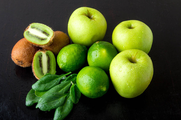 Ingredients for smoothie. Green fruits on black wooden background. Apple, lime, spinach, kiwi. Detox. Healthy food. - Foto, afbeelding