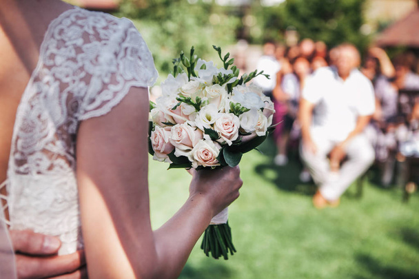 La mariée tenant un bouquet de mariage devant les invités
 - Photo, image