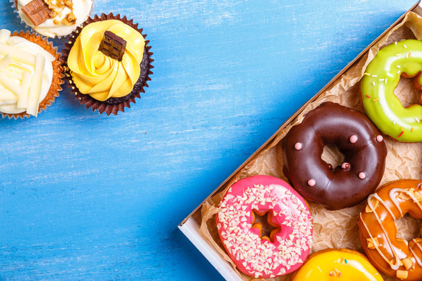 Glazed donuts and cupcakes with cream. - Фото, зображення