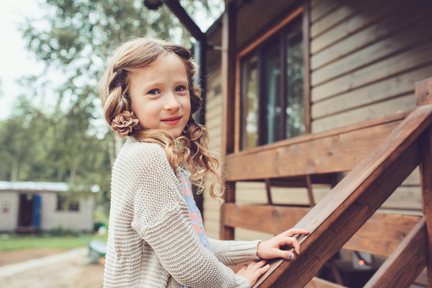kid girl playing at wooden cabin in the woods. Child spending summer vacation outdoor at country house - Fotoğraf, Görsel
