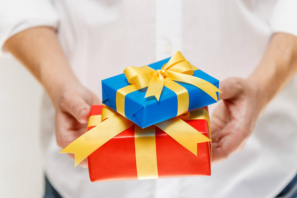 Male hands holding a gift boxes with ribbon. - Photo, Image