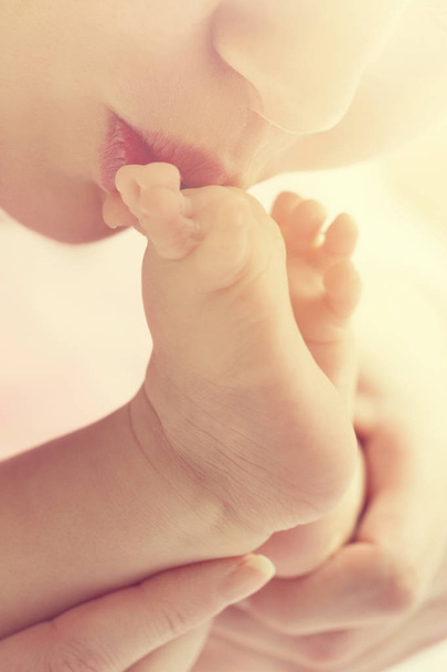 Mother kisses baby feet, closeup. Daylight. Selective focus.  - Valokuva, kuva