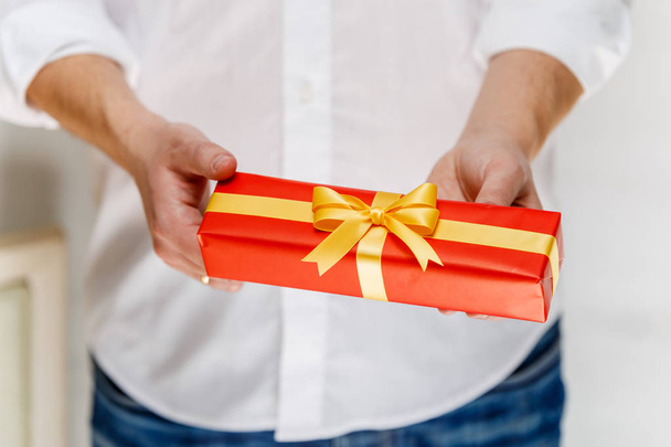 Male hands holding a red gift box with ribbon. - Photo, Image